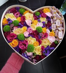 Flower composition in heart box with Geisha candies