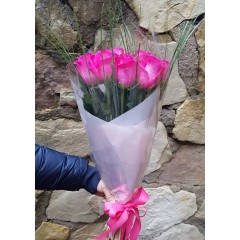 Rozā rožu pušķis dekoratīvā iepakojumā
